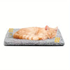 An orange tabby cat is lying on a gray, textured pet bed mat.