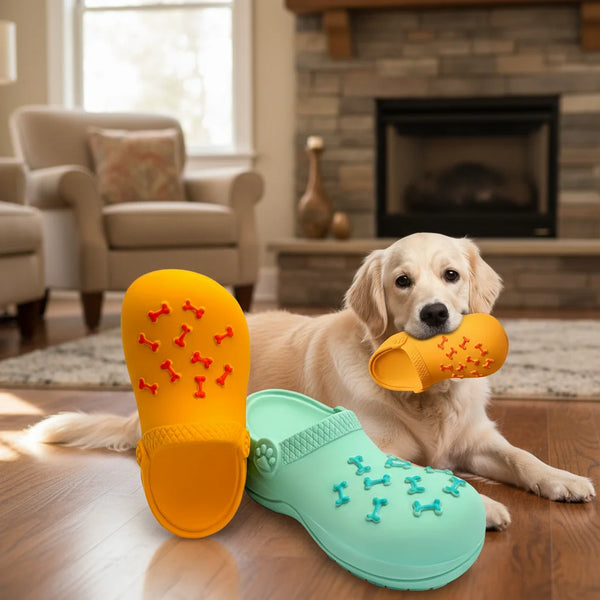 A golden retriever lies next to bright orange rubber dog toys for teeth cleaning and training.
