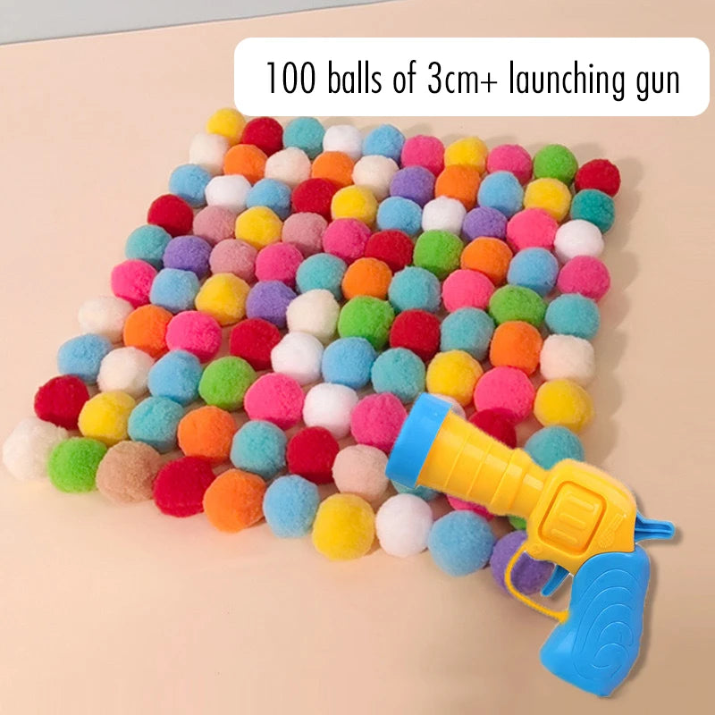 A colorful array of 100 plush balls is arranged in a line next to a yellow launching gun.