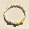 A circular necklace made of pastel floral beads, featuring soft pink, yellow, and green tones.