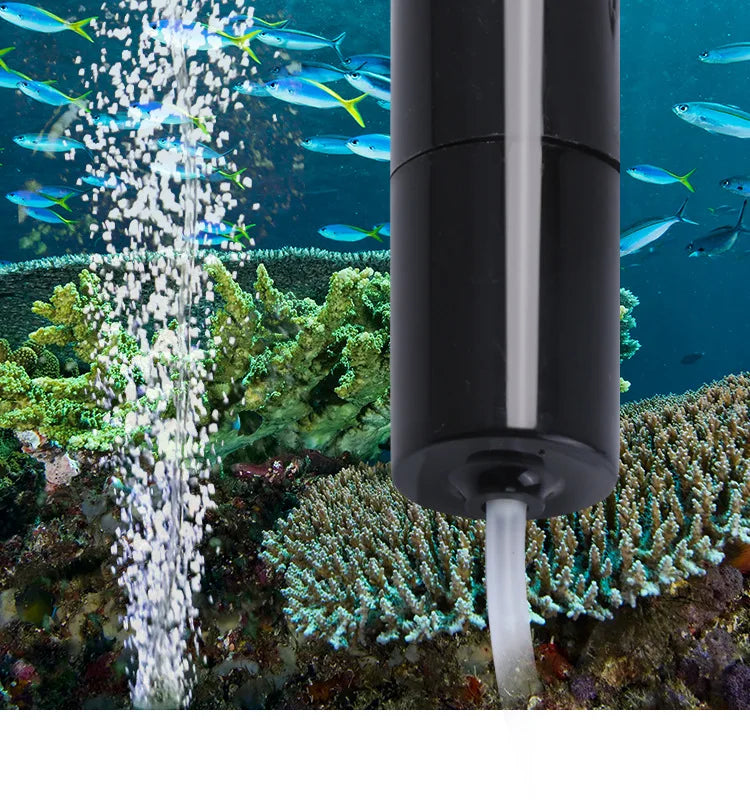 A black portable USB aquarium oxygen pump is shown operating an air stream in a marine environment with fish and coral.