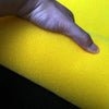 A hand is pressing on a bright yellow, porous sponge filter.
