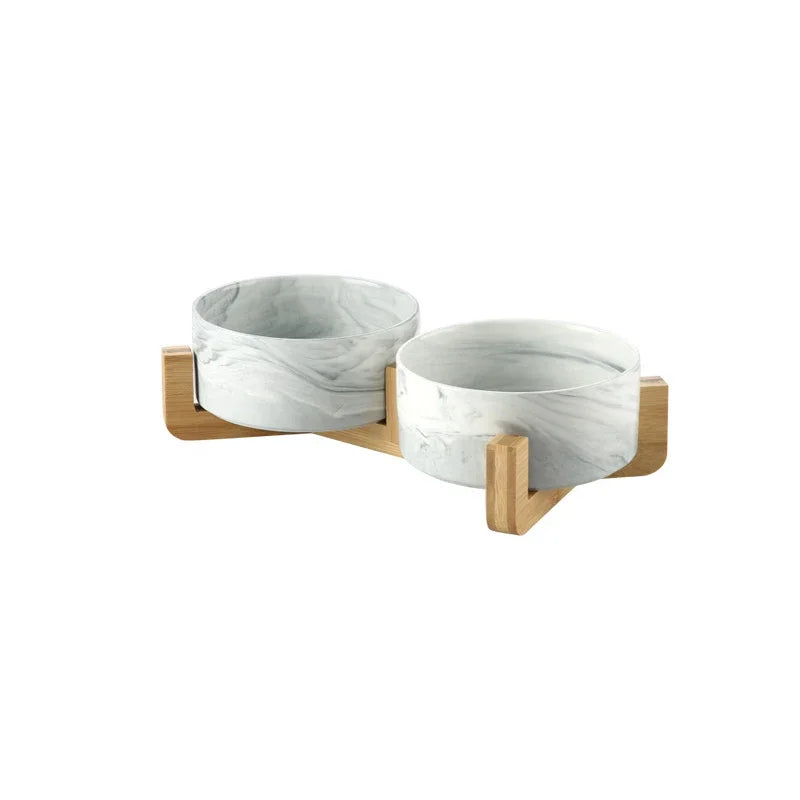 A set of two marbled ceramic pet bowls with a wooden stand.