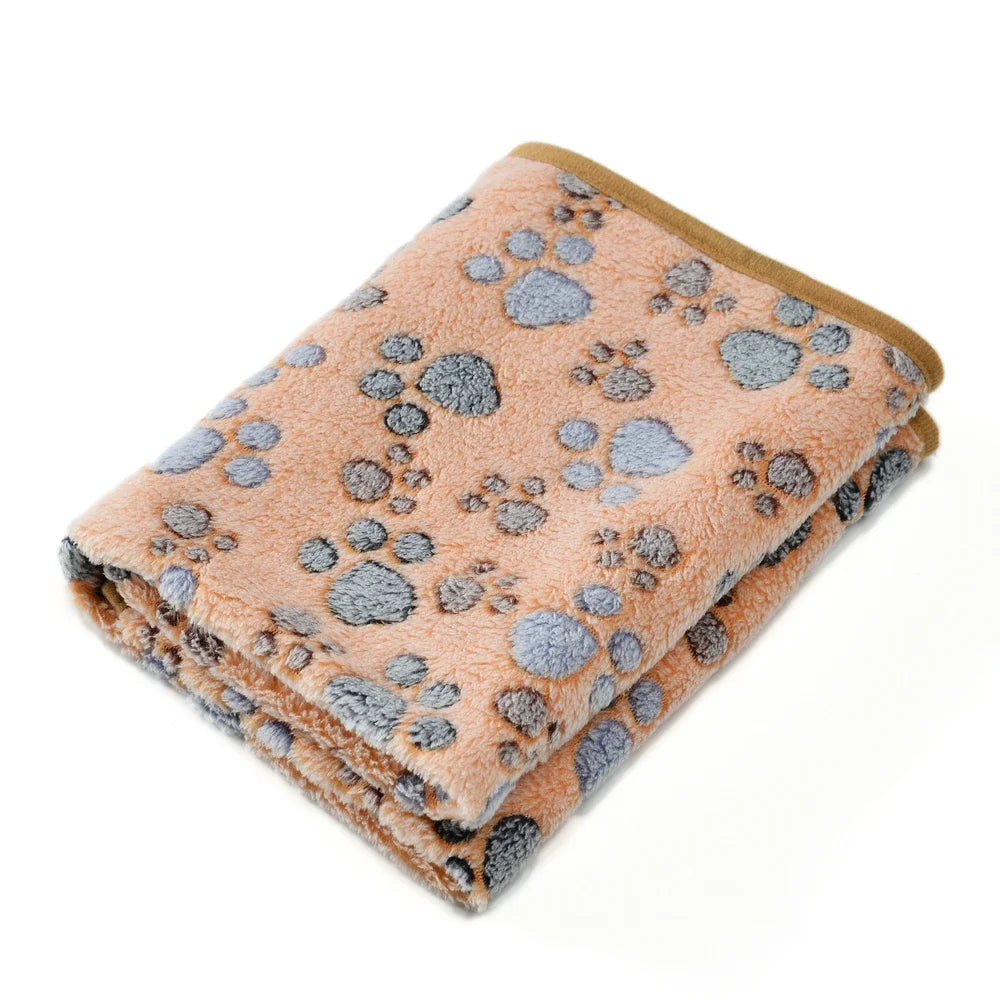 A thick fleece pet blanket in a peach color with a gray paw print pattern.