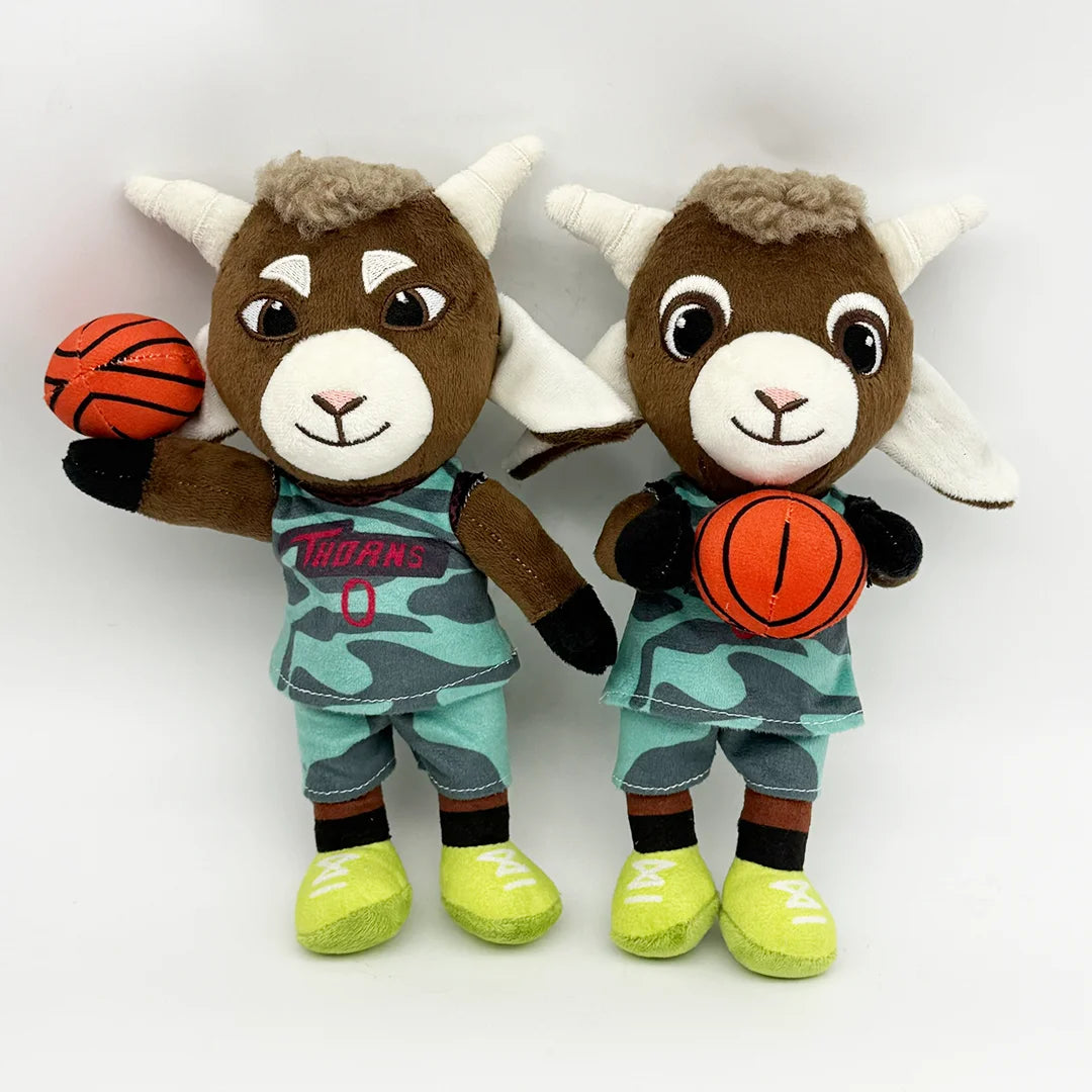 A brown goat plush toy with white horns wearing a teal and black sports uniform and holding an orange ball.