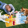 A dog and a person are interacting with a yellow blanket filled with various scented items for pet sniffing training.