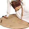 A model wears a brown cropped top and white pants while laying out a tan foldable travel organizer bag with a picnic mat.