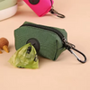 A dark green zippered pouch with a black carabiner attached, next to a crumpled green plastic bag.