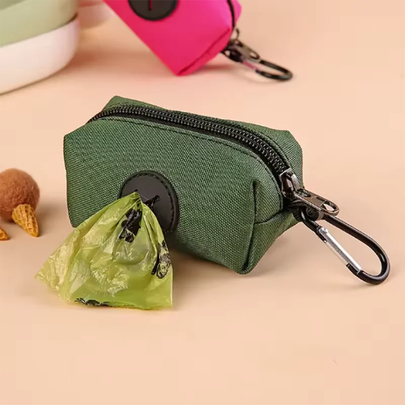 A dark green zippered pouch with a black carabiner attached, next to a crumpled green plastic bag.