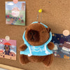 Braune Capybara-Plüsch-Hoodiepuppe mit hellblauer Stoff und weißem Zierrand auf einer Korkwand
