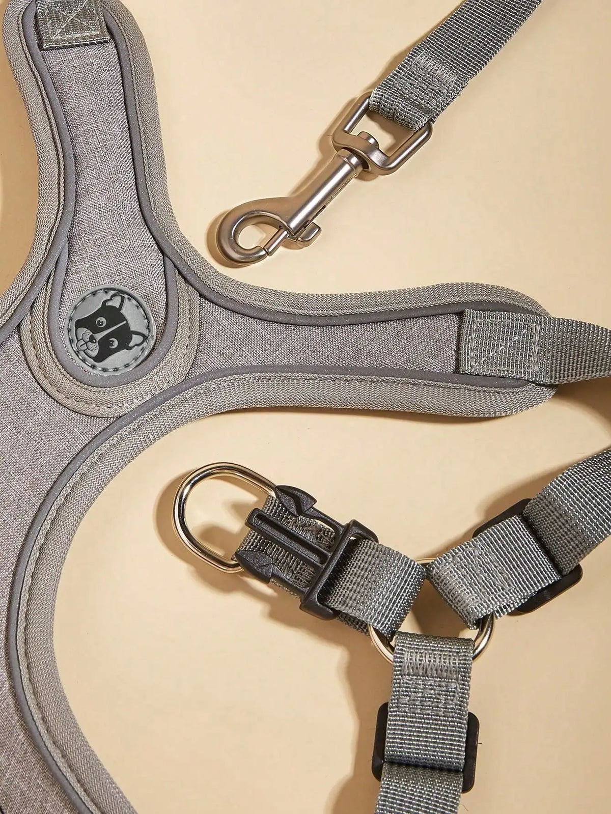A gray comfort fit dog harness and leash set with a silver clip and a circular emblem.