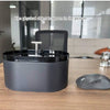 A dark gray automatic cat water fountain bowl sitting on a wooden table.