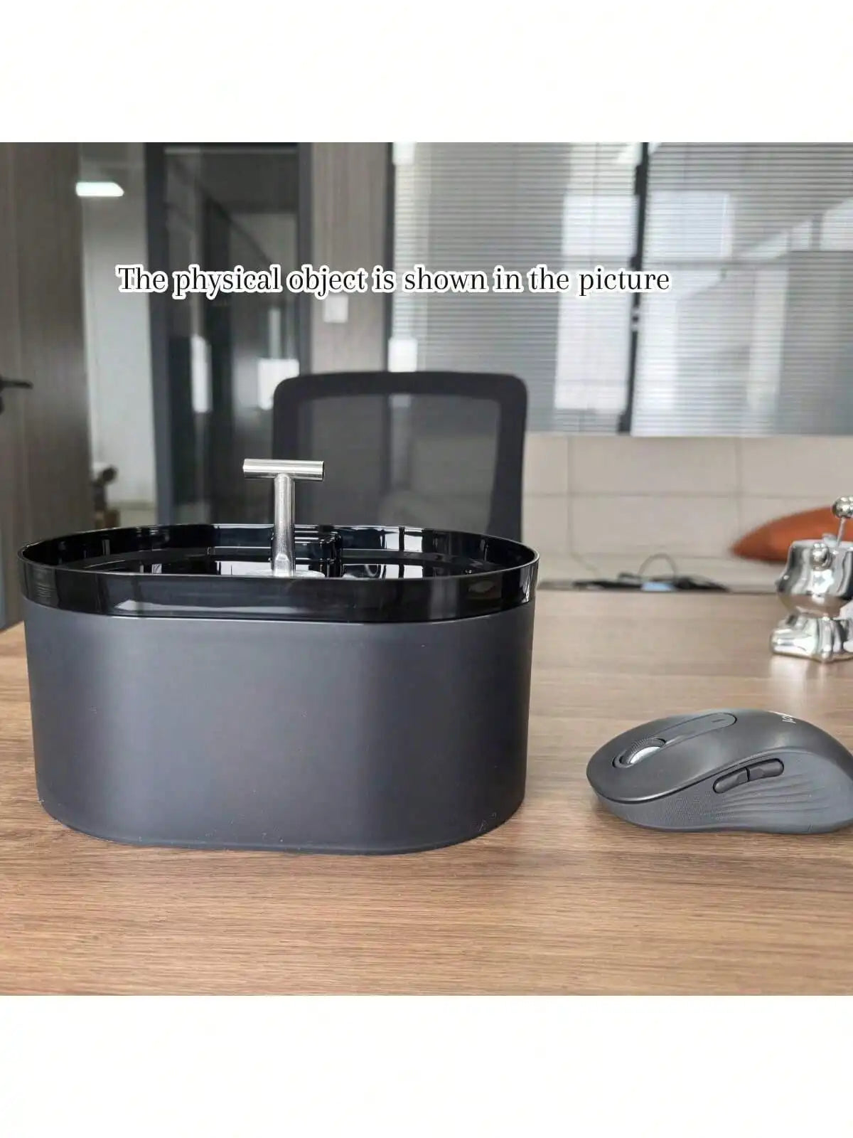 A dark gray automatic cat water fountain bowl sitting on a wooden table.