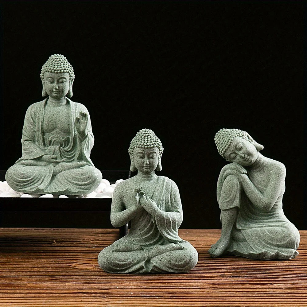 A grey stone statue of the Buddha seated in meditation on a wooden surface.