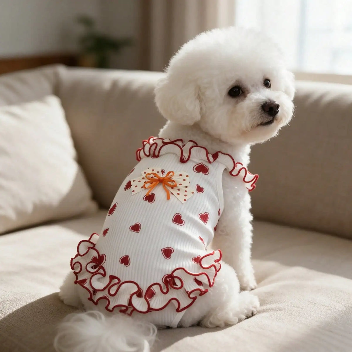 A fluffy white puppy wearing a red heart bow ruffle sleeveless tank top.