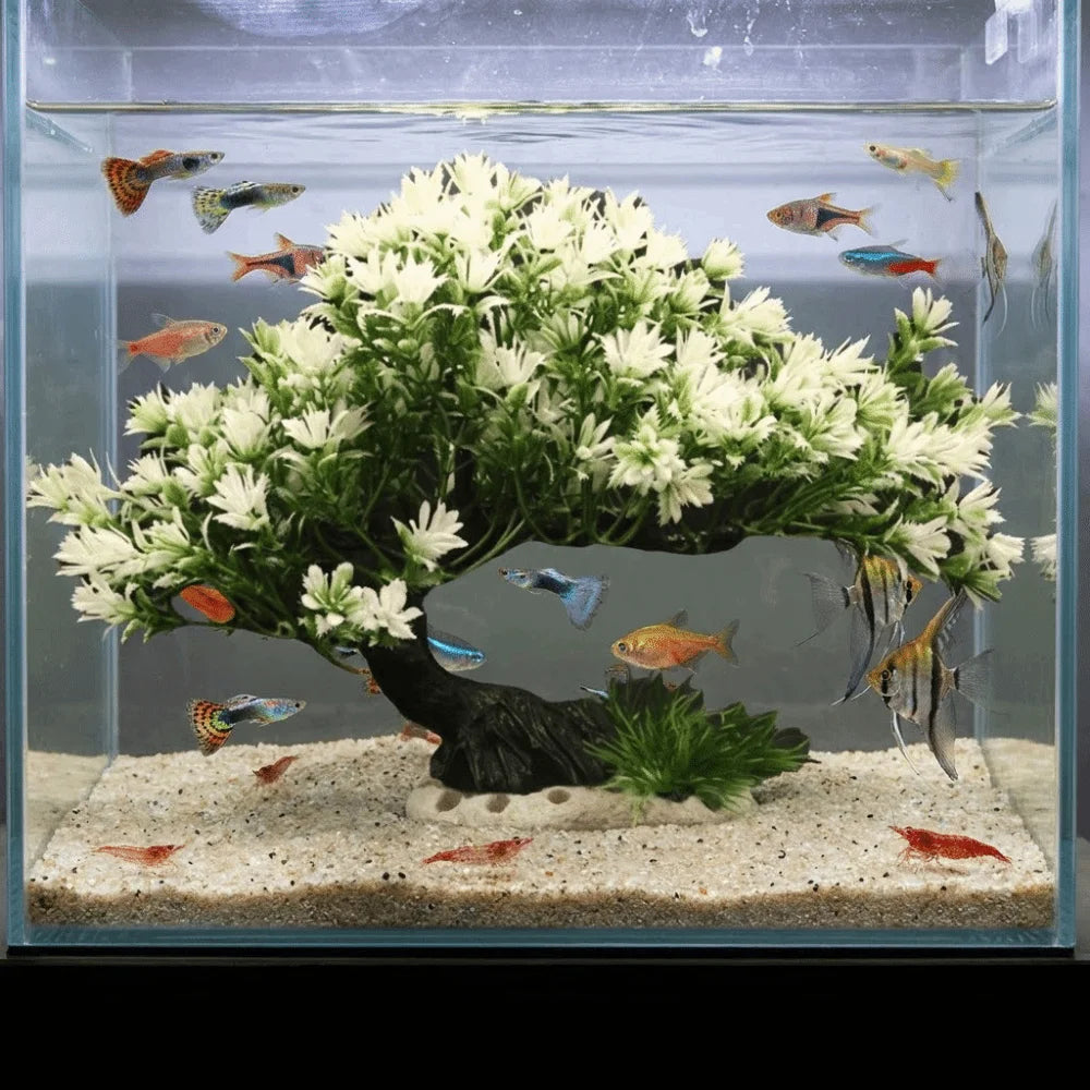 Lifelike artificial aquarium plant shaped like a pine tree with white flowers and colorful fish in a glass tank