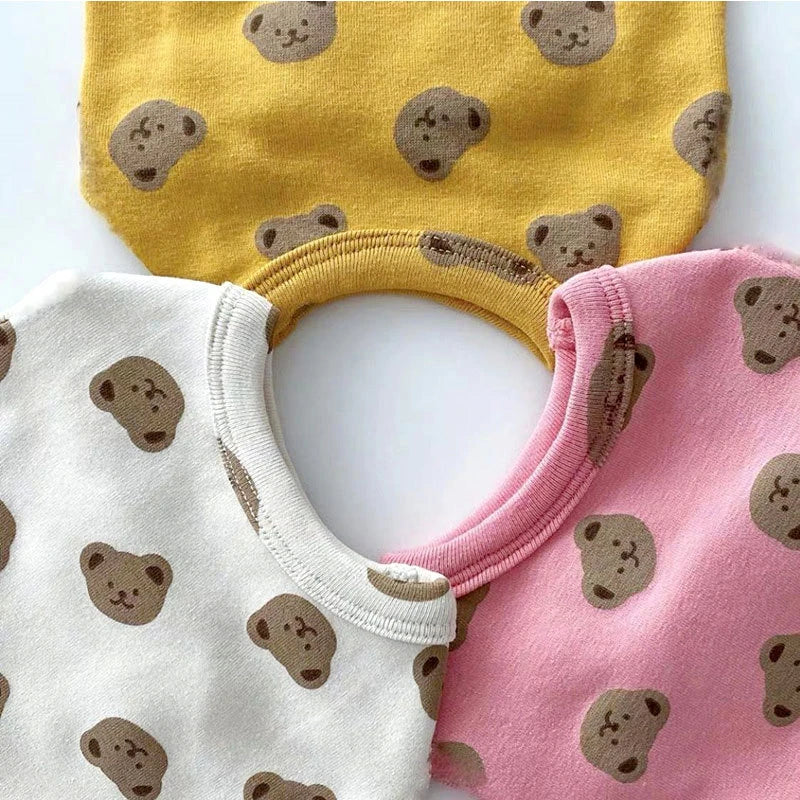 Three knitted pet vests for dogs in yellow, white, and pink with cartoon bear prints.