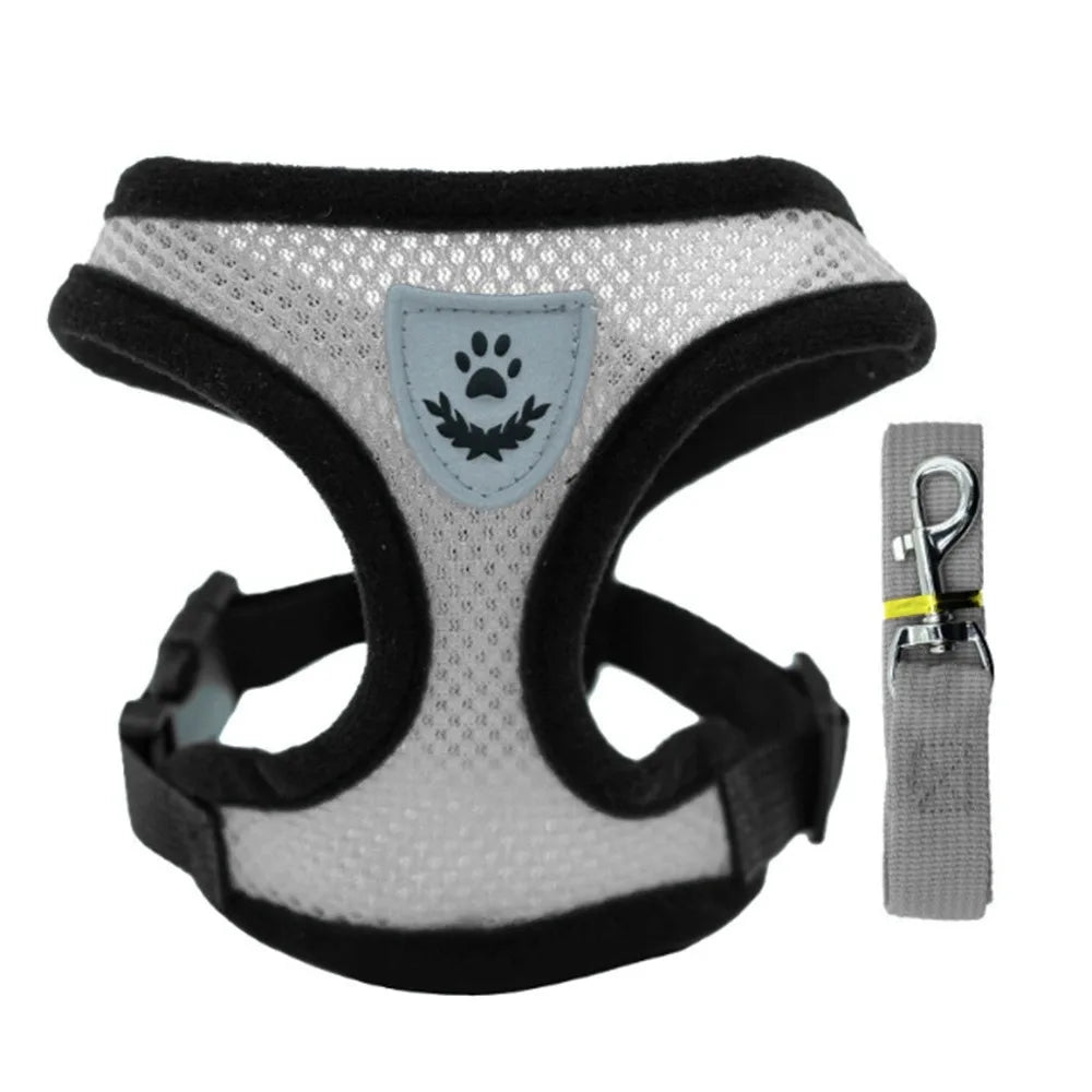 A black and gray mesh pet harness vest with a silver paw print emblem and an attached reflective strap.