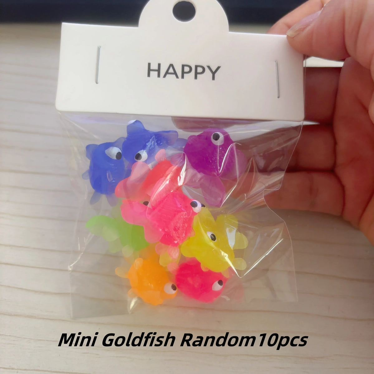 A clear plastic bag contains ten colorful mini goldfish bath toys, including blue, pink, purple, and yellow varieties.