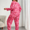 A woman models a pink heart print pajama set featuring small red hearts on a long-sleeved top and matching pants.