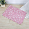 A pink and white patterned washable pet training mat for dogs lying on a light wooden floor.