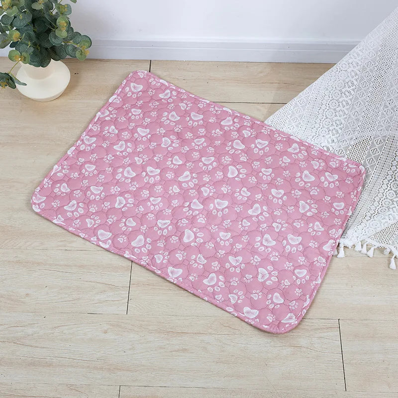 A pink and white patterned washable pet training mat for dogs lying on a light wooden floor.