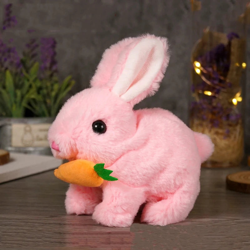 A pink plush bunny toy with long ears and an orange carrot accessory sitting on a wooden surface.