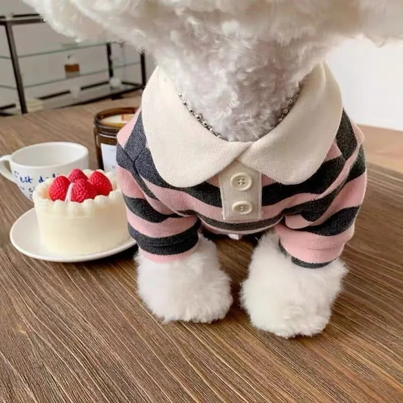 Flauschiges weißes Hundekostüm mit rosa-schwarz gestreiftem West und hellem Kragen.
