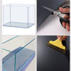A clear acrylic box is shown next to a pair of scissors and a yellow tool used for cutting or shaping film.