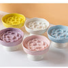 A set of ceramic elevated bowls in yellow, white, purple, and blue for pets.