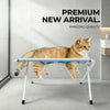 A fluffy orange tabby cat is relaxing on a white foldable pet grooming hammock station.