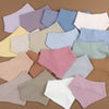 A collection of pink, beige, and blue cotton baby bibs for newborns arranged on a brown surface.
