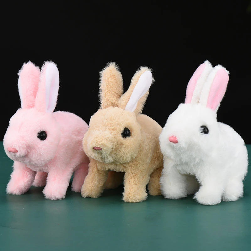 Three plush bunnies in pink, beige, and white standing side by side against a dark background.
