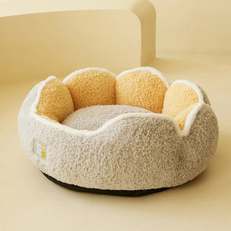 Runde, beige Plüschkattennestbett mit weichen gelben und weißen Akzenten auf einer hellen Oberfläche.