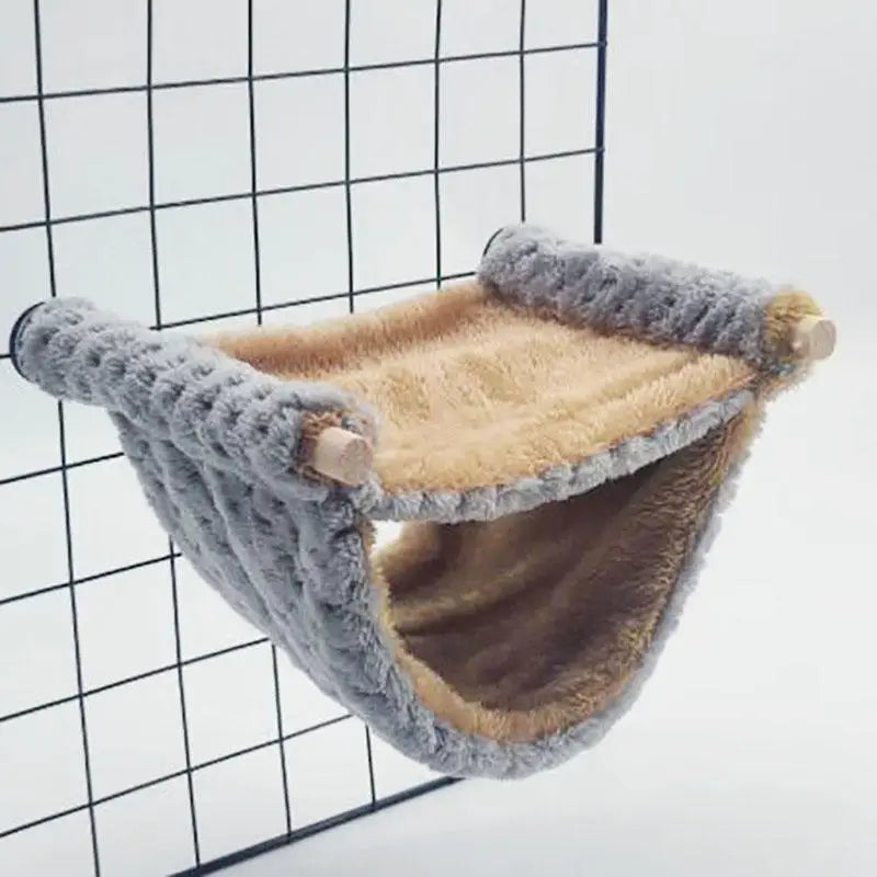 Gemütliches Kuschelhampchen für Haustiere aus grauem und tanigem Kunstfell vor einem schwarzen Drahtgitter.