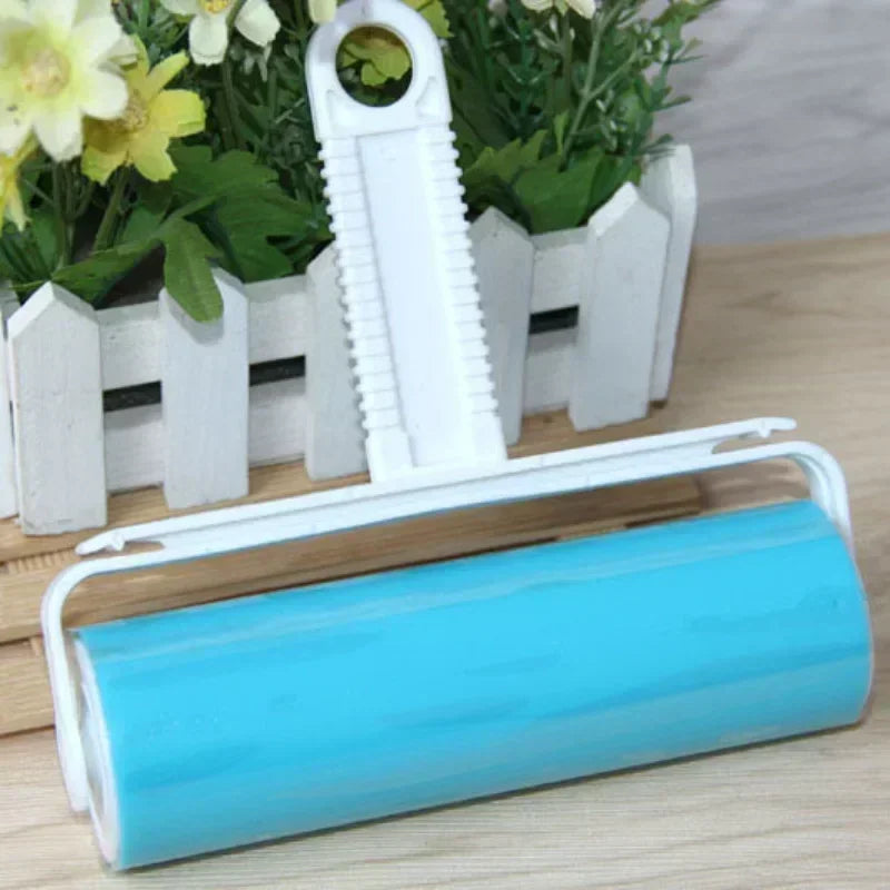 A blue reusable lint roller with a white handle is shown next to potted plants.