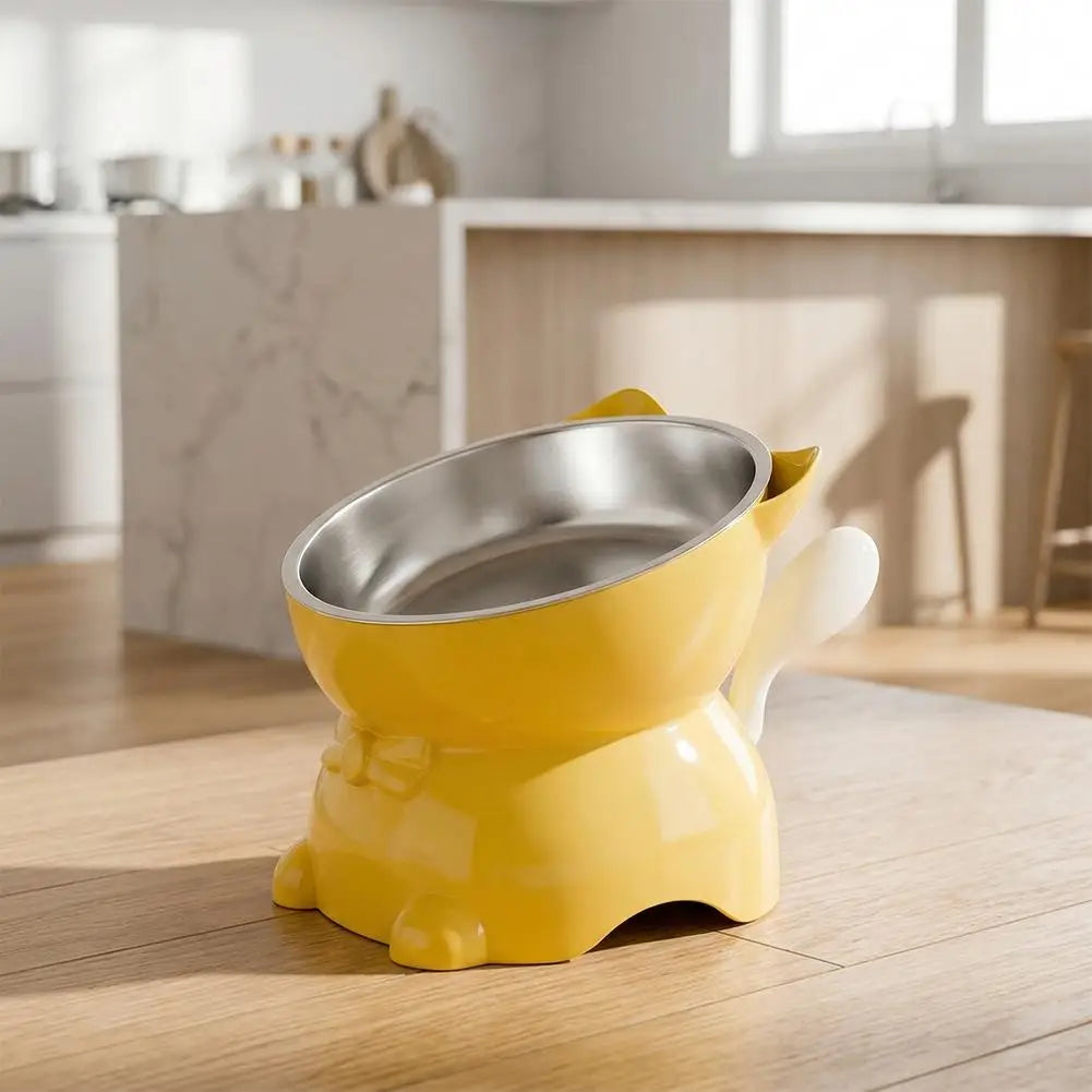 A yellow elevated cat bowl with a stainless steel insert sitting on a wooden table.