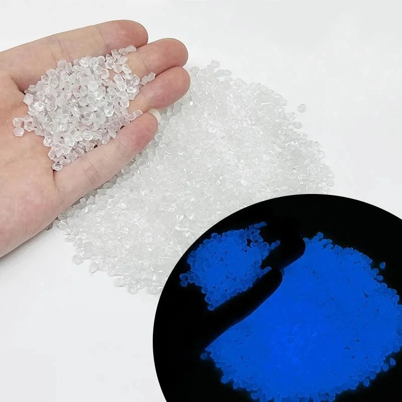 A hand holds clear glow-in-the-dark decorative pebbles, with a magnified view showing the blue light they emit.