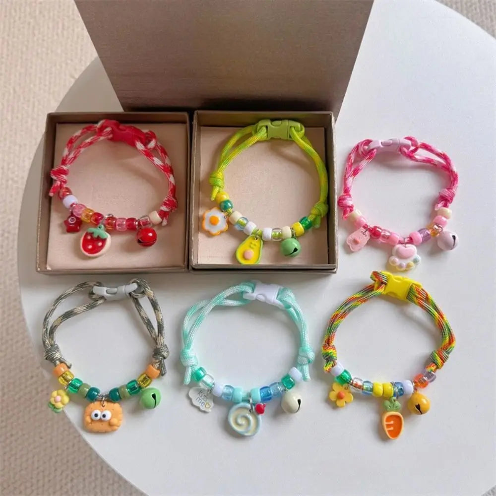A collection of colorful braided pet collars with bells for cats and small dogs displayed in a cardboard box.