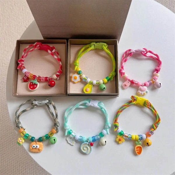 A collection of colorful braided pet collars with bells for cats and small dogs displayed in a cardboard box.