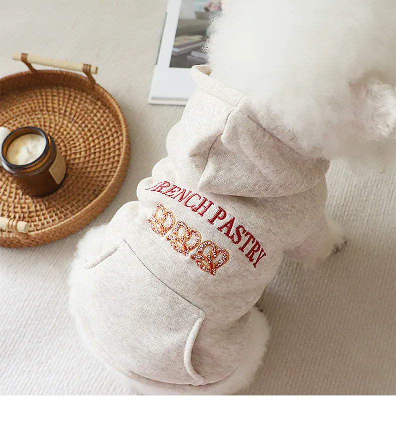 A light beige embroidered hoodie for a small dog with red lettering on the chest