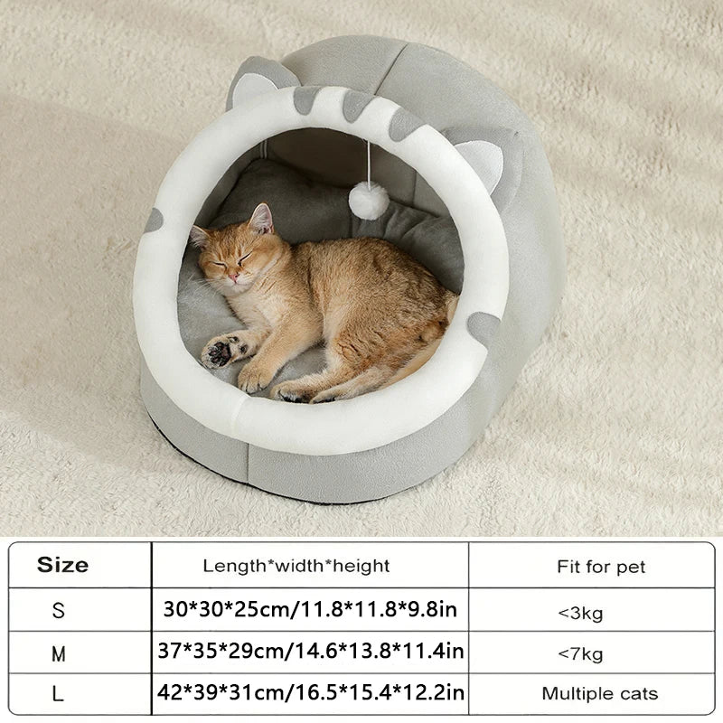 A fluffy orange cat is relaxing inside a round, gray pet cave bed with a decorative rim.