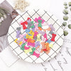 A plate filled with multi-colored dog hair clips for pet grooming, arranged in various shades of pink, purple, green, and yel