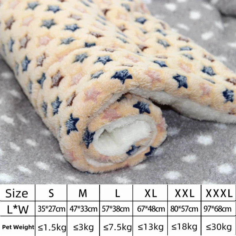 Un lit pour animal en flanelle roulé et confortable avec un motif d'étoiles beige clair et bleu sur une surface grise.