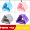 Four colorful plush bird nests in blue, pink, gray, and purple hanging from hooks for parrots