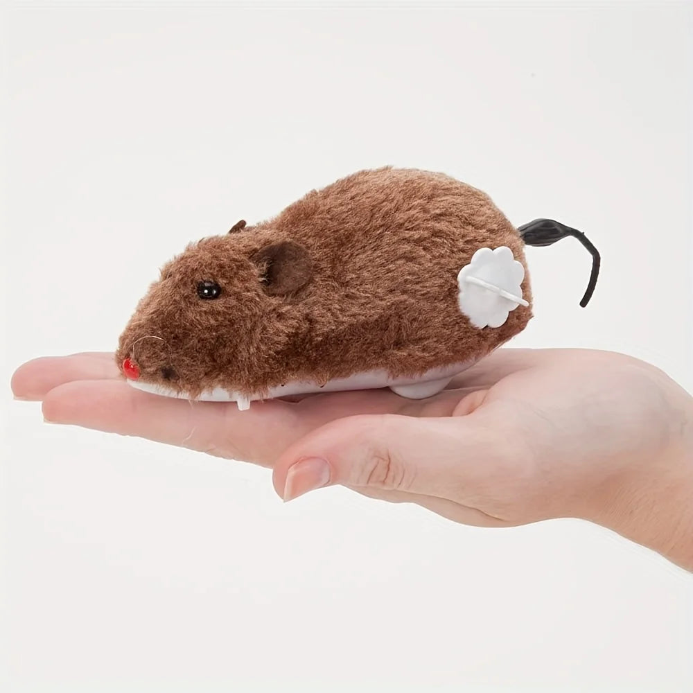 A brown plush mouse toy is held in a person's hand against a white background.