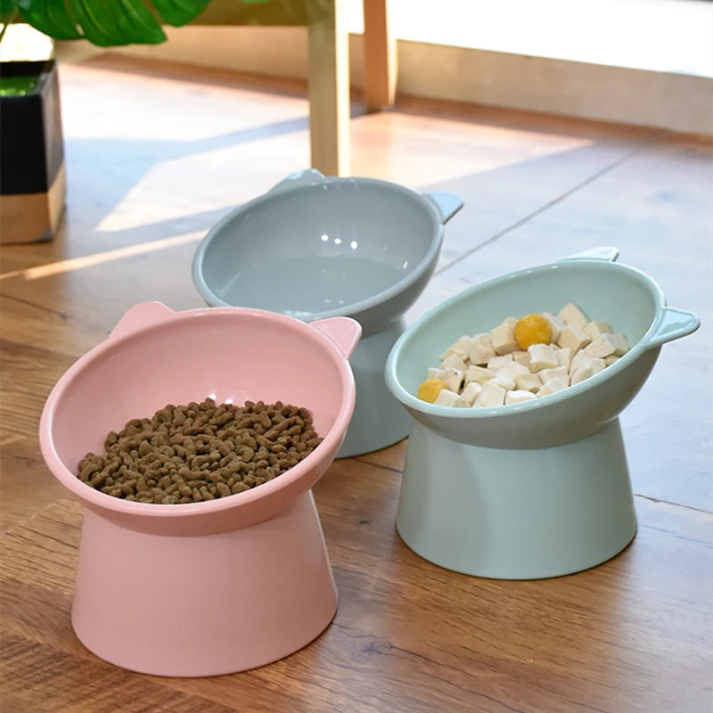 A set of pink and light green ergonomic elevated pet bowls for feeding cats and dogs on a wooden floor.