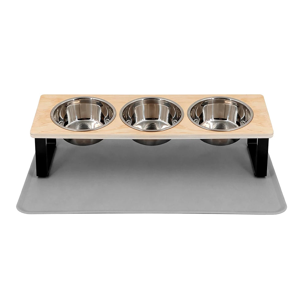 A wooden stand with three stainless steel bowls and a gray feeding mat for pet food.