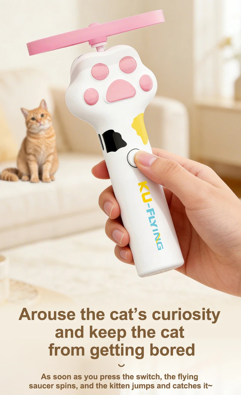 A hand holds a pink and white interactive cat wand toy with a flying saucer attachment, designed to engage cats.