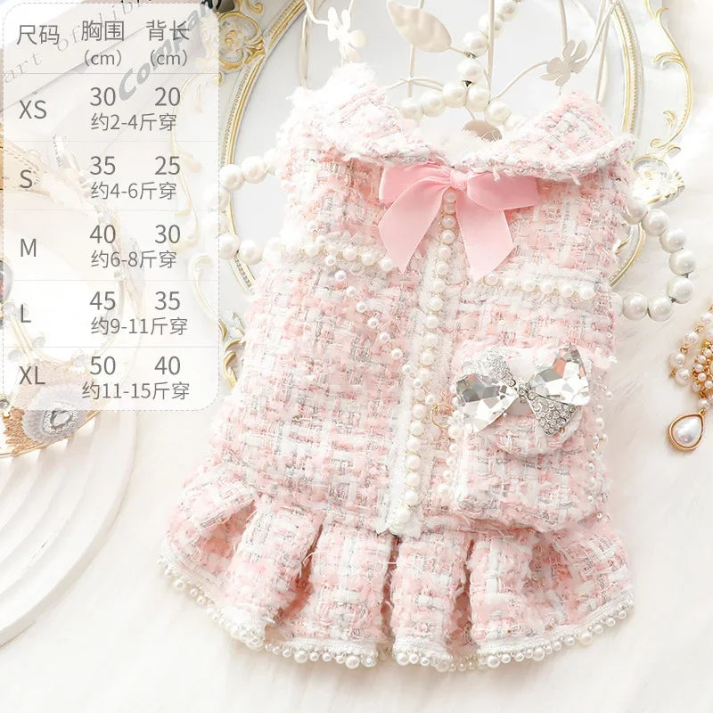 Robe tricotée rose texturée pour enfant avec nœud et bordure de perles sur fond blanc.